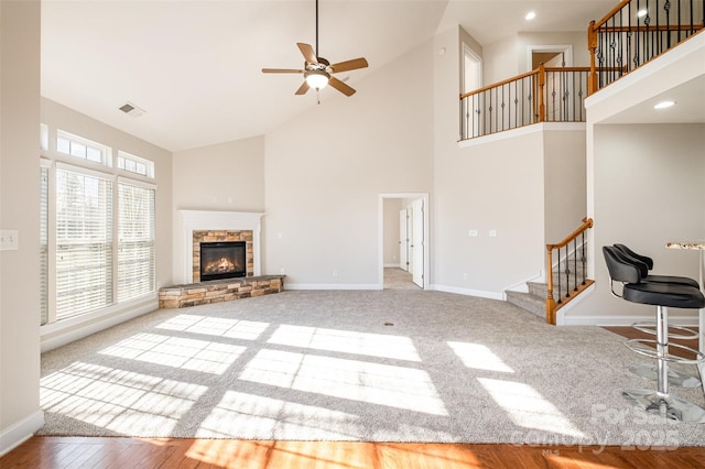 unfurnished living room featuring high vaulted ceiling, ceiling fan, light colored carpet, and a fireplace