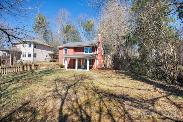 back of property featuring a lawn, a chimney, and fence