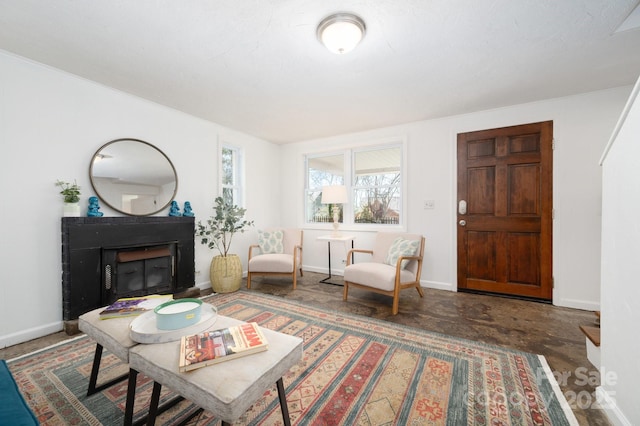 living area featuring a fireplace with raised hearth, concrete floors, and baseboards