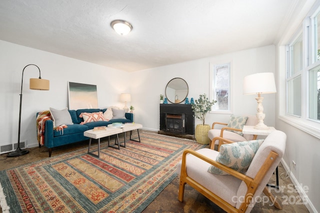 living area with baseboards, concrete floors, visible vents, and a fireplace with raised hearth