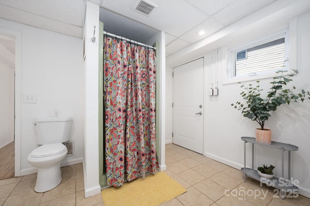 bathroom featuring a paneled ceiling, visible vents, toilet, and tile patterned floors