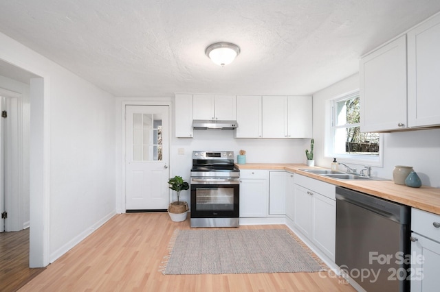 kitchen with under cabinet range hood, a sink, white cabinets, wooden counters, and appliances with stainless steel finishes