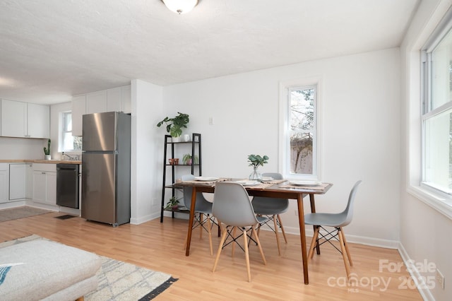 dining area with light wood finished floors and baseboards