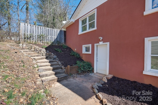 doorway to property with fence and stucco siding