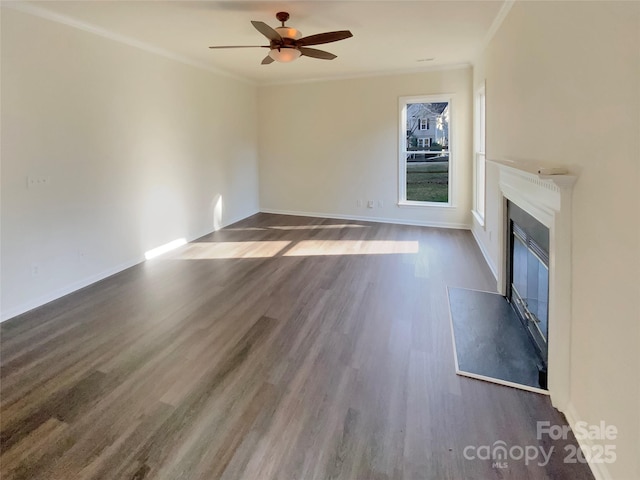 unfurnished living room featuring dark wood-type flooring, a glass covered fireplace, and crown molding