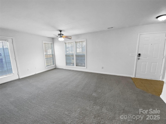 unfurnished living room featuring dark colored carpet, visible vents, ceiling fan, and baseboards