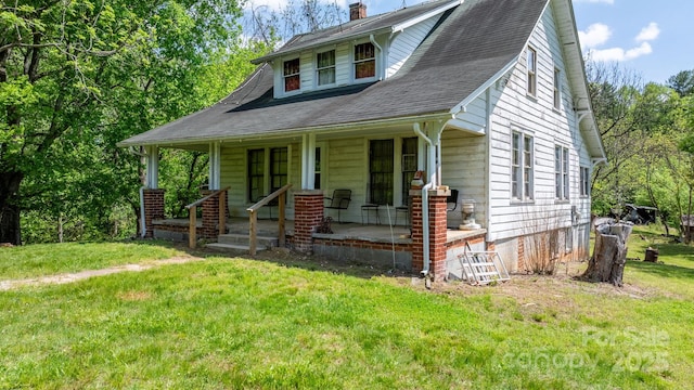 bungalow featuring a chimney, a porch, and a front yard