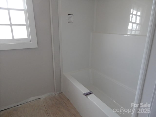 bathroom with wood-type flooring and a bath