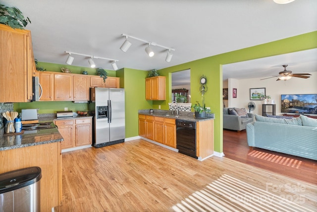 kitchen featuring dark stone countertops, appliances with stainless steel finishes, sink, light wood-type flooring, and ceiling fan