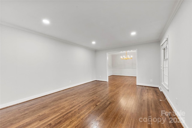 unfurnished room with dark wood finished floors, crown molding, an inviting chandelier, and baseboards