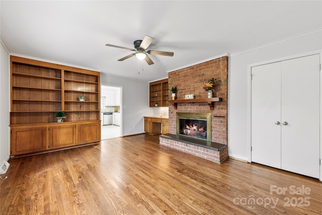 unfurnished living room featuring ceiling fan, light wood finished floors, ornamental molding, and a fireplace