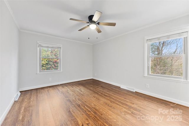 spare room with baseboards, visible vents, a healthy amount of sunlight, and wood finished floors