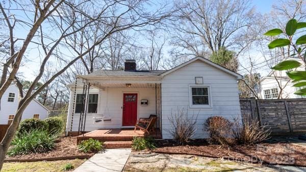 bungalow featuring fence, covered porch, and a chimney