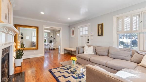 living area with a fireplace, crown molding, and wood finished floors