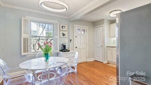 dining space featuring light wood-style flooring, baseboards, and ornamental molding