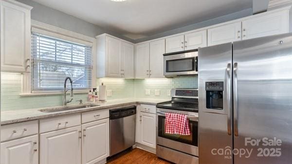 kitchen featuring a sink, white cabinets, decorative backsplash, and stainless steel appliances