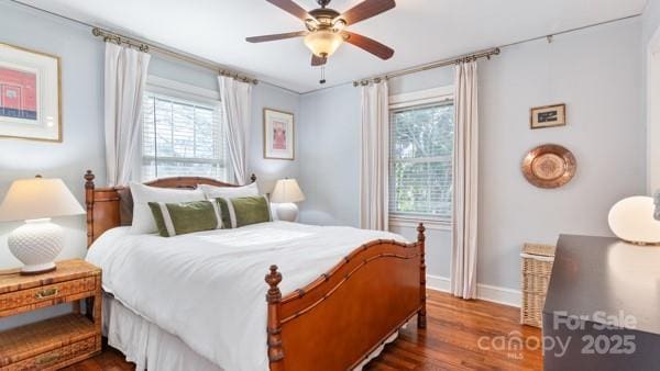 bedroom featuring a ceiling fan, baseboards, dark wood-style floors, and multiple windows