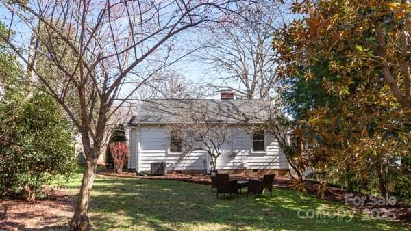 back of house featuring a chimney and a yard