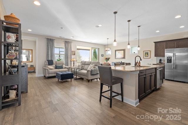 kitchen with wood finished floors, stainless steel appliances, a sink, and open floor plan