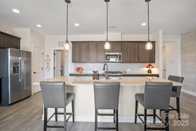 kitchen with dark wood-style flooring, stainless steel appliances, visible vents, a sink, and dark brown cabinetry