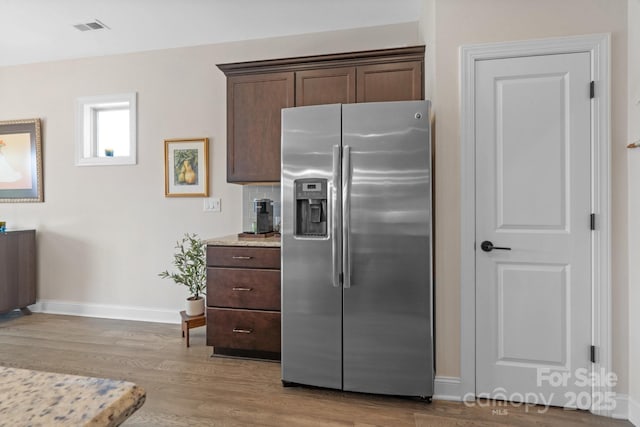 kitchen featuring stainless steel fridge, baseboards, visible vents, wood finished floors, and dark brown cabinets