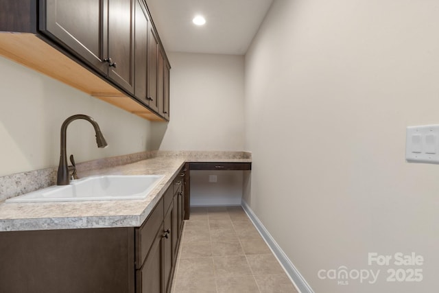 laundry room featuring recessed lighting, light tile patterned flooring, a sink, and baseboards