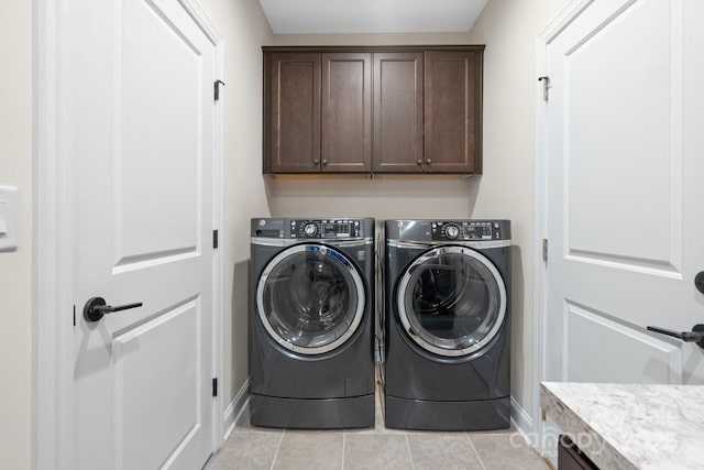 clothes washing area featuring cabinet space, baseboards, light tile patterned flooring, and washing machine and clothes dryer