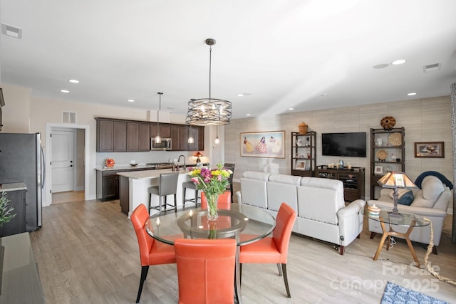 dining area with light wood-type flooring, visible vents, and recessed lighting