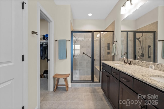 bathroom featuring a stall shower, a walk in closet, tile patterned flooring, and a sink