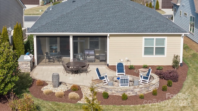 back of property with a patio, an outdoor fire pit, a shingled roof, and a sunroom