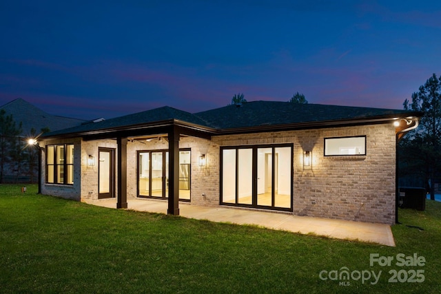 back house at dusk with a patio, a yard, and cooling unit