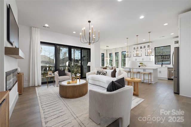 17201 Green Hill Rd, Charlotte, NC 28278 - living room with recessed lighting, a wealth of natural light, a fireplace, light wood-type flooring, and a notable chandelier