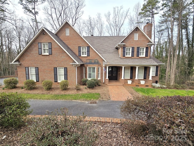 view of front facade with crawl space, a porch, a chimney, and brick siding