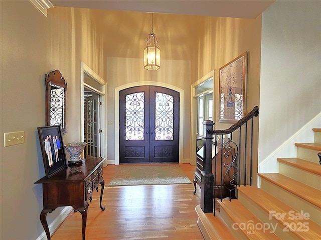 foyer entrance with stairs, baseboards, wood finished floors, and french doors