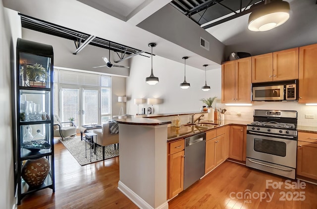 kitchen featuring a peninsula, visible vents, appliances with stainless steel finishes, dark countertops, and pendant lighting