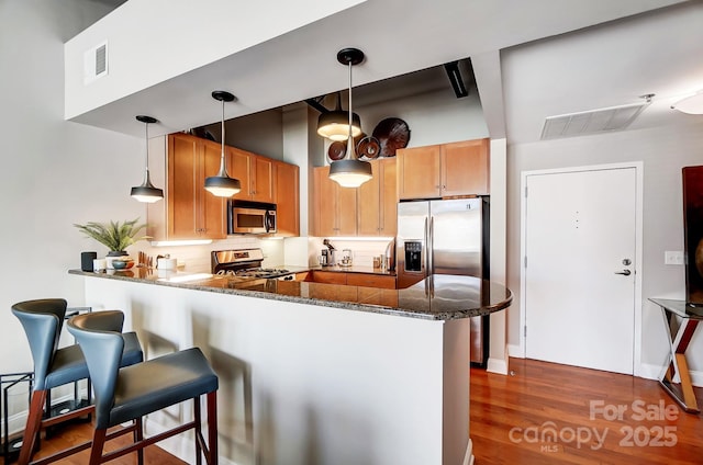 kitchen featuring stainless steel appliances, a peninsula, and decorative light fixtures