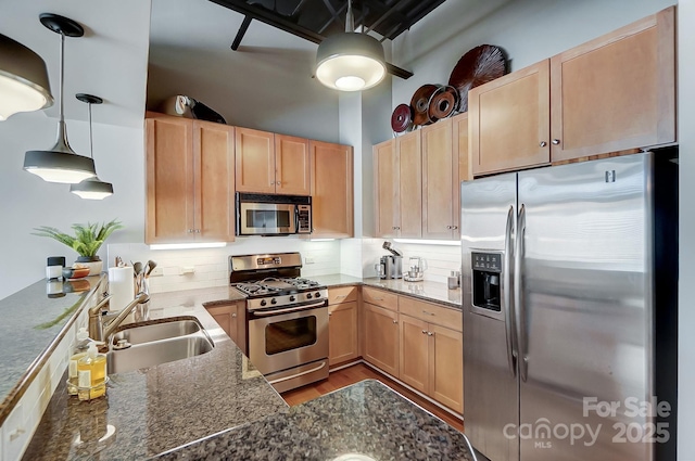 kitchen with light brown cabinets, hanging light fixtures, appliances with stainless steel finishes, and a sink