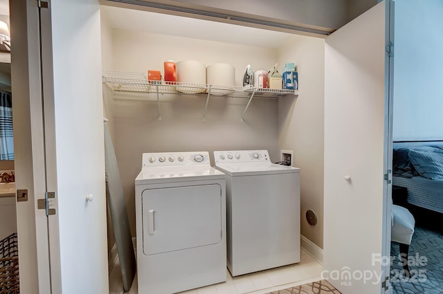 washroom featuring laundry area, independent washer and dryer, light tile patterned flooring, and baseboards