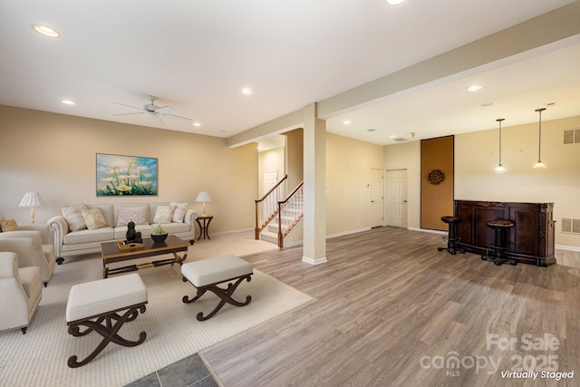 living room with a dry bar, visible vents, wood finished floors, stairs, and recessed lighting