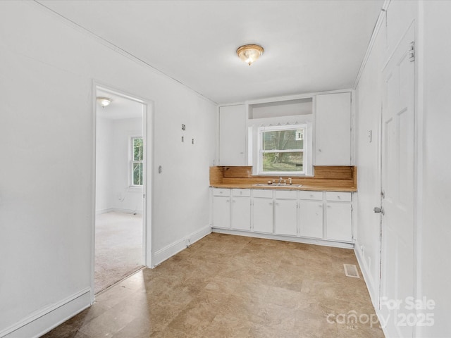 kitchen with plenty of natural light, sink, white cabinetry, and decorative backsplash