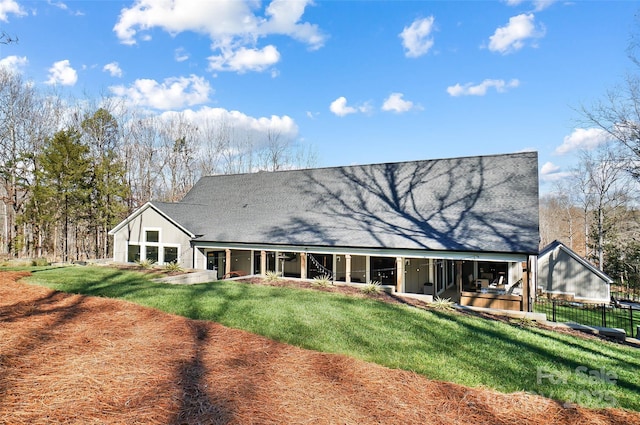 rear view of house with a lawn and fence