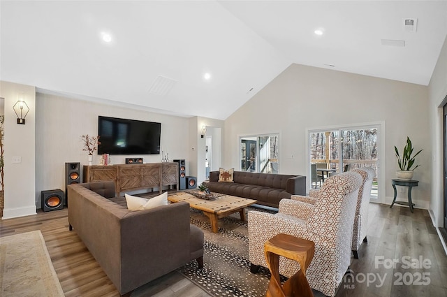 living area featuring light wood finished floors, baseboards, and high vaulted ceiling