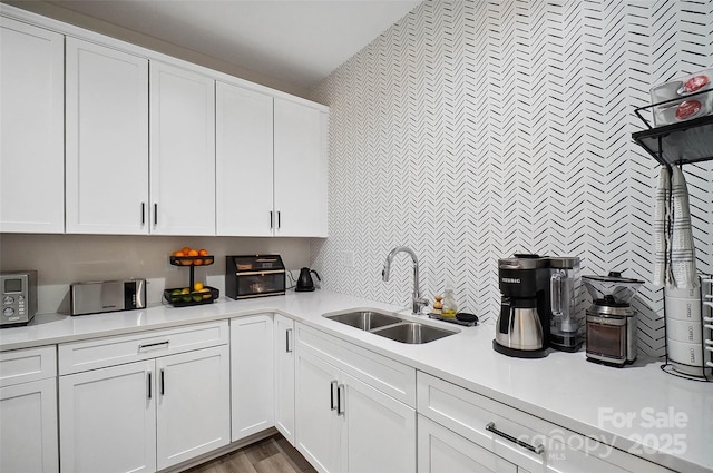 kitchen with white cabinets, light wood-style flooring, light countertops, and a sink