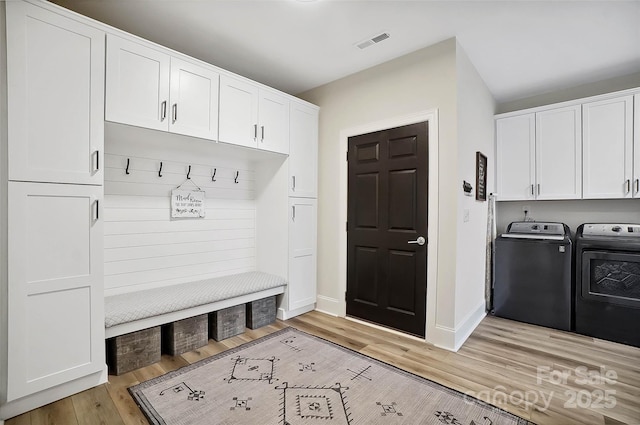 mudroom featuring baseboards, light wood finished floors, visible vents, and washer and dryer