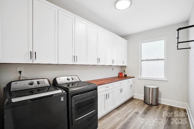 laundry area featuring baseboards, light wood-style flooring, cabinet space, and washer and dryer