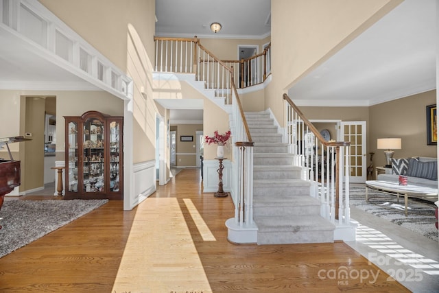 entrance foyer featuring crown molding, a towering ceiling, and wood-type flooring