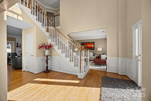 entryway featuring hardwood / wood-style flooring, a towering ceiling, and crown molding