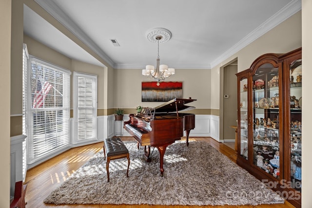 sitting room with a notable chandelier, wood-type flooring, and ornamental molding