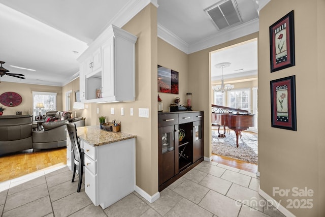 kitchen with white cabinetry, ceiling fan with notable chandelier, light stone countertops, and crown molding