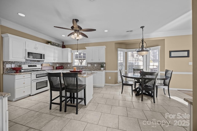 kitchen featuring white cabinetry, double oven range, backsplash, a kitchen island, and light stone countertops